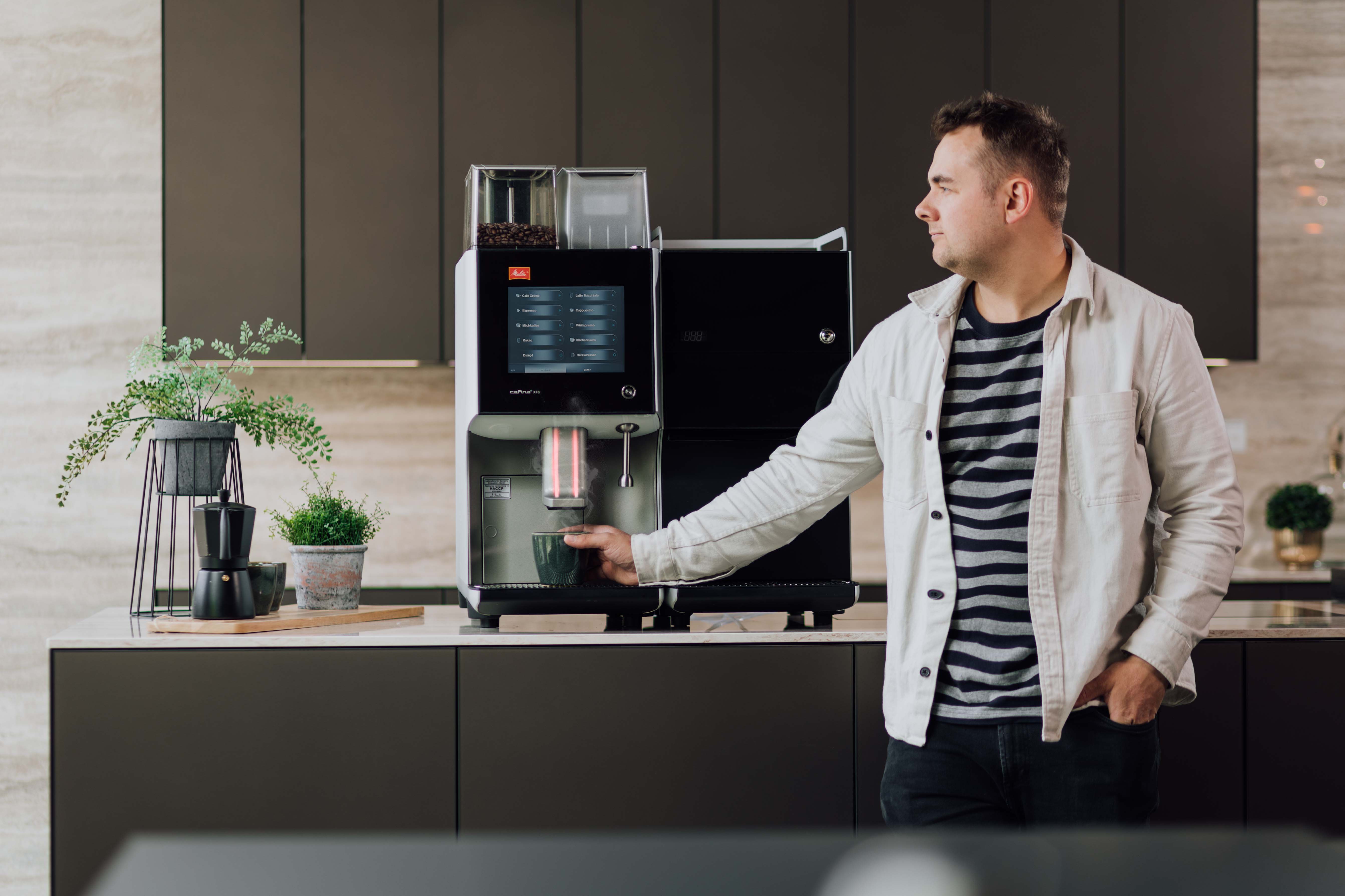 En ansatt i bedriften og en helautomatisk kaffemaskin. Kaffemaskin bedrift